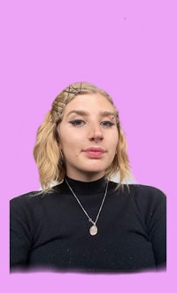 a woman wearing a black top and necklace on a pink background